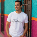 A person wearing a short-sleeved white T-shirt with the word 'Tabasco' printed in black script on the front.