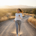 A woman standing, wearing carbon gray sweatpants with a drawstring waist, two front pockets, and ribbed cuffs. She has a white top and is wearing white sneakers.