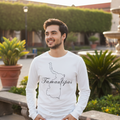 A man wearing a white long-sleeve t-shirt with a black outline map of the state of Tamaulipas and the word 'Tamaulipas' written in script, standing outdoors in a sunny plaza with stone benches and greenery.