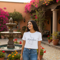 A woman wearing a white short-sleeved crop t-shirt with the text 'Tamaulipas' printed on the front, paired with blue jeans.