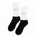 A pair of black and white Tlaxcala socks displayed upright on a surface with dried lavender surrounding them. The socks have the word 'Tlaxcala' written on the white cuff.