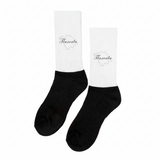 A pair of black and white Tlaxcala socks displayed upright on a surface with dried lavender surrounding them. The socks have the word 'Tlaxcala' written on the white cuff.
