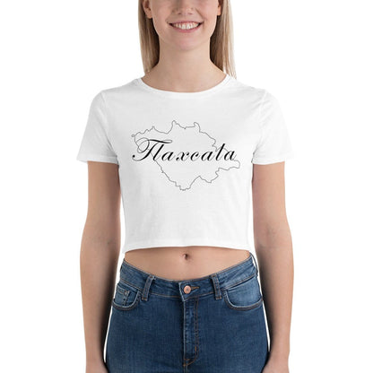 A woman wearing a white short-sleeved crop t-shirt with the word 'Tlaxcala' printed in black script on the front, paired with blue jeans.