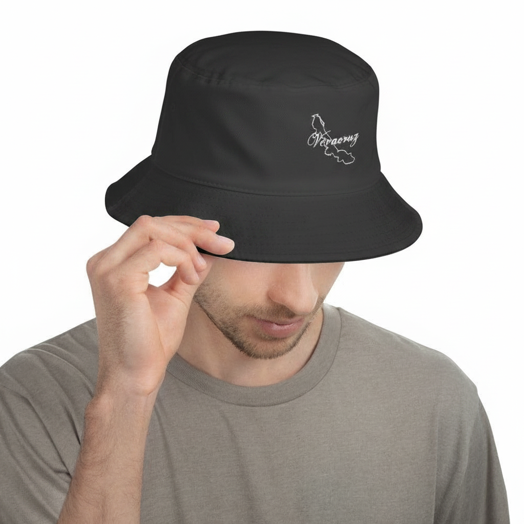 A man wearing a black bucket hat with a white outline graphic of the state of Maine and the word 'Maine' on the front, holding the brim with one hand against a plain white background.