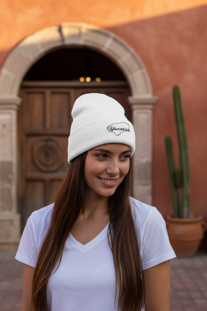 A person wearing a white embroidered beanie hat with the text 'Yucatan' on it.