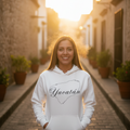 A woman wearing a white hoodie with the word 'Yucatán' printed in black script on the front.