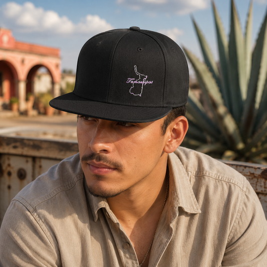 A man wearing a black baseball cap with a white embroidered outline of Tamaulipas and the text 'Tamaulipas' on the front, photographed outdoors with a blurred background of a desert landscape and sky.